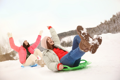 Photo of Happy friends having fun and sledding on snow. Winter vacation