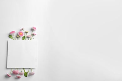 Photo of Flat lay composition with blooming daisies and space for text on white background. Spring flowers