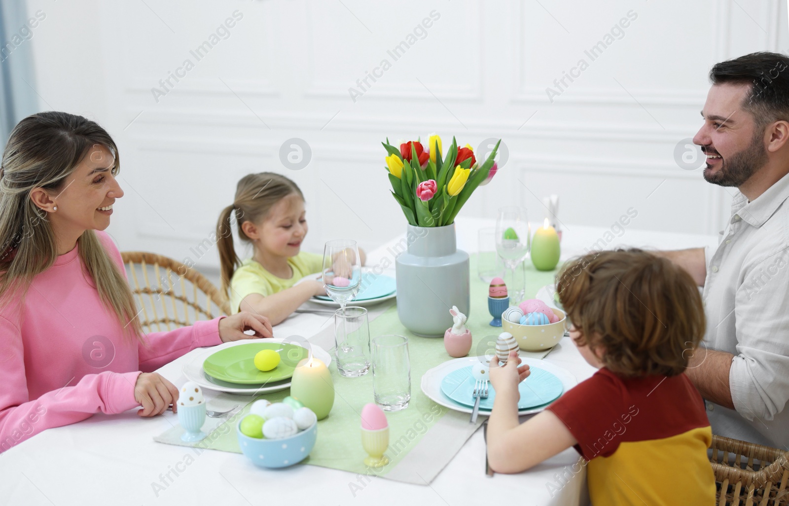 Photo of Cute family celebrating Easter at served table in room