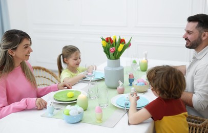 Cute family celebrating Easter at served table in room