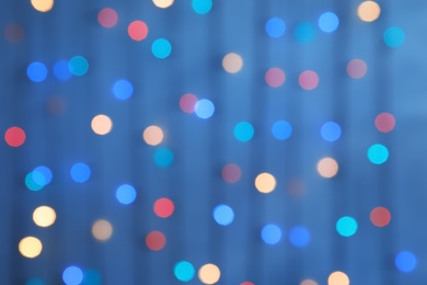 Blurred view of Christmas lights on color background