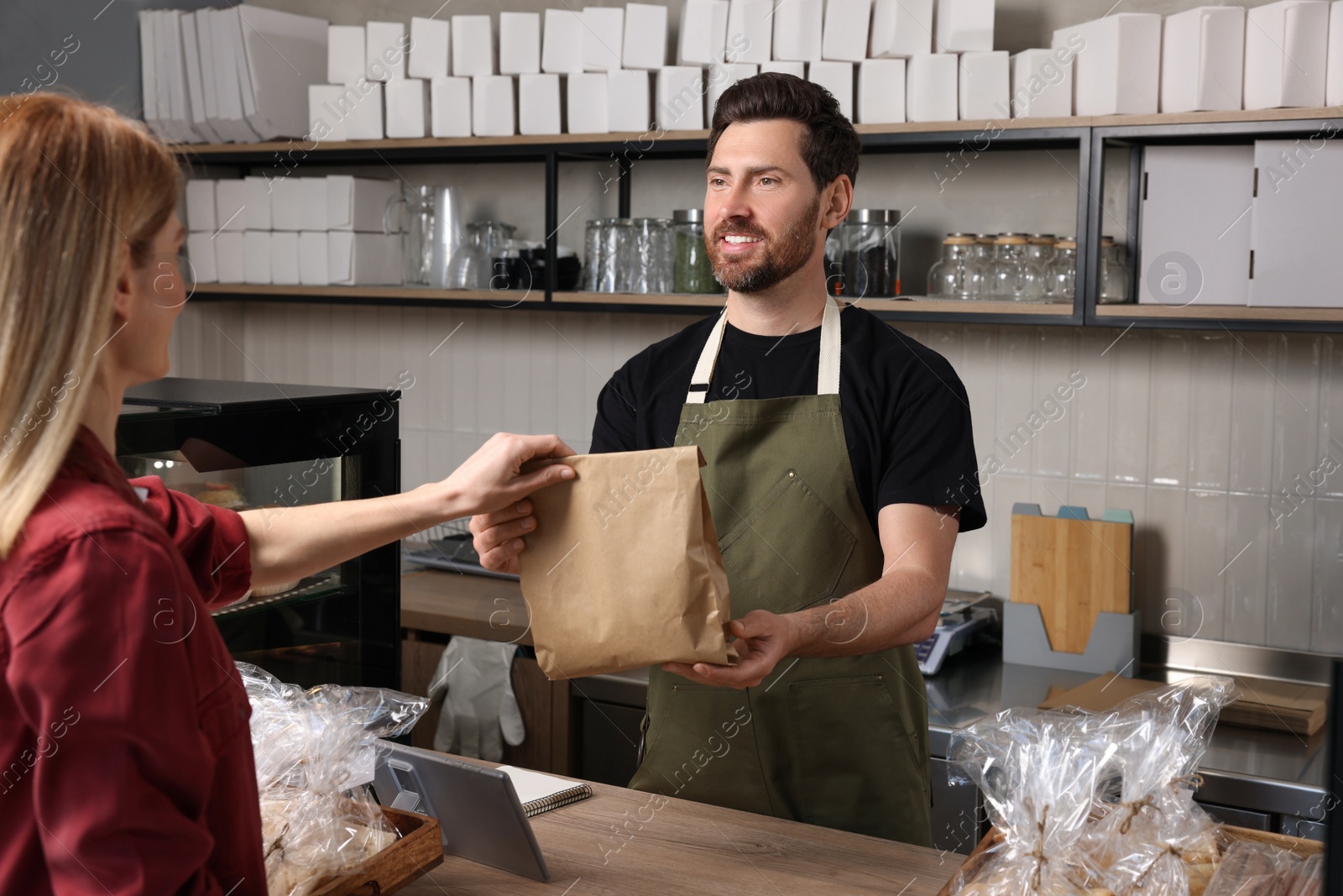 Photo of Seller giving customer fresh pastries in bakery shop