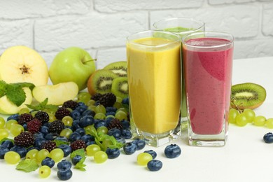 Photo of Fresh colorful fruit smoothies and ingredients on white table