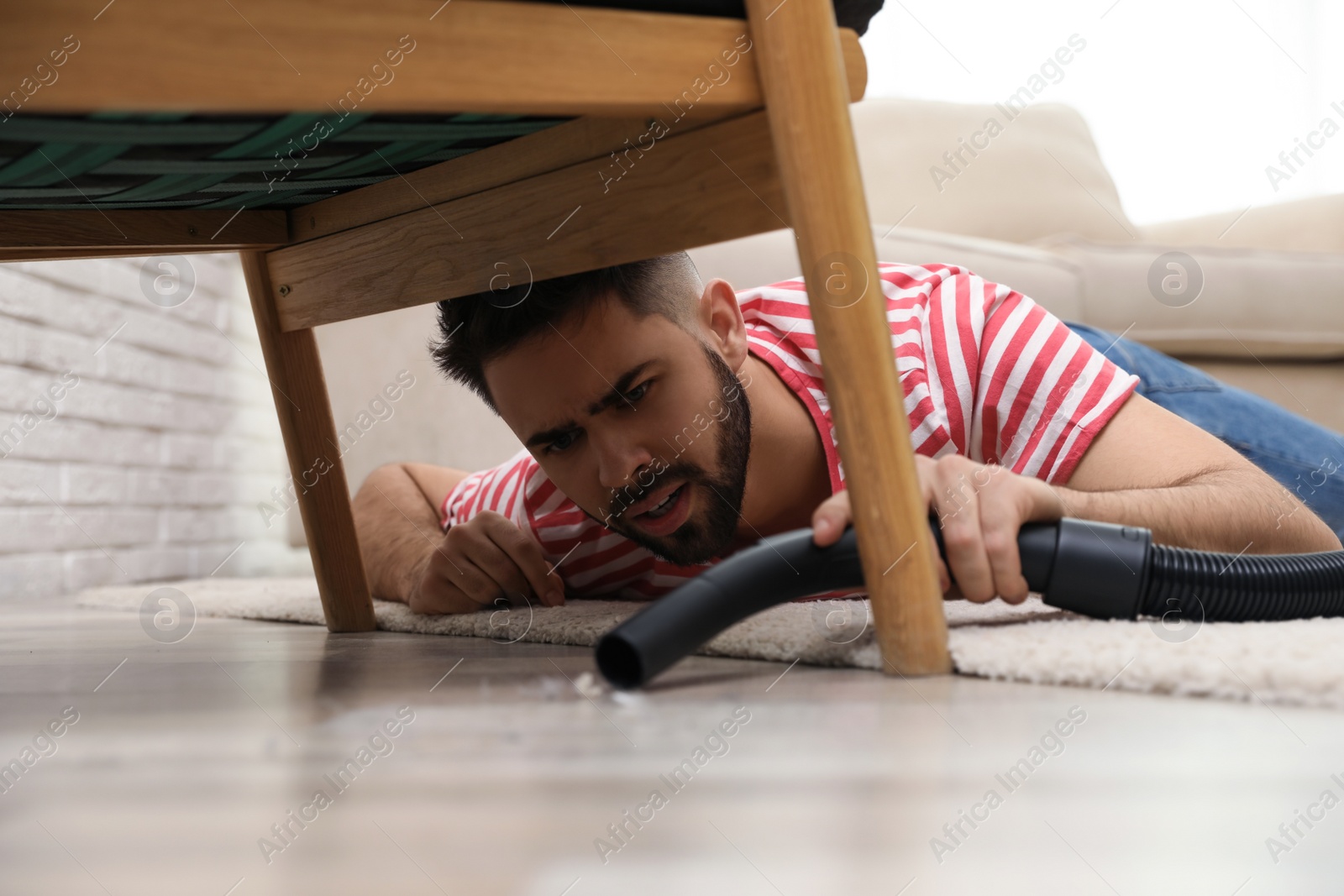 Photo of Young man using vacuum cleaner at home