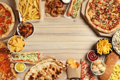 French fries, pizza and other fast food on wooden table, flat lay with space for text