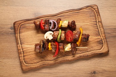 Delicious shish kebabs with vegetables on wooden table, top view