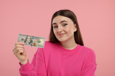 Sad woman with dollar banknote on pink background