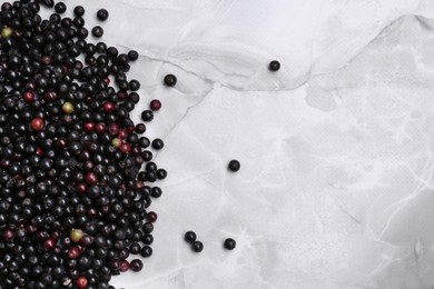 Photo of Pile of tasty elderberries (Sambucus) on white marble table, flat lay. Space for text
