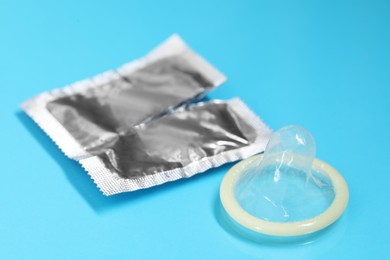 Torn condom package on light blue background. Safe sex