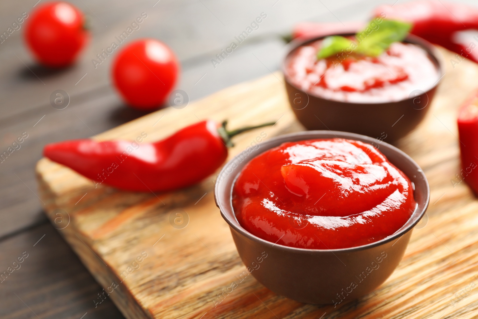 Photo of Bowl with spicy chili sauce on wooden table