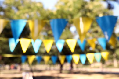 Photo of Blurred view of colorful bunting flags in park. Party decor