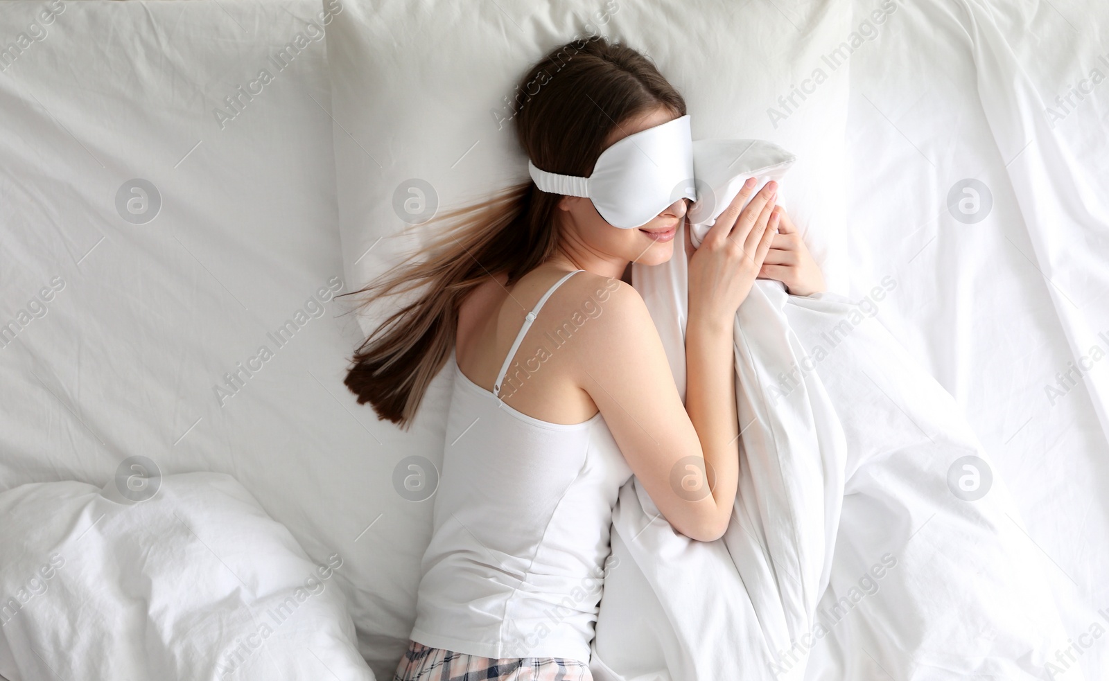 Photo of Young woman sleeping on comfortable pillow in bed at home, top view