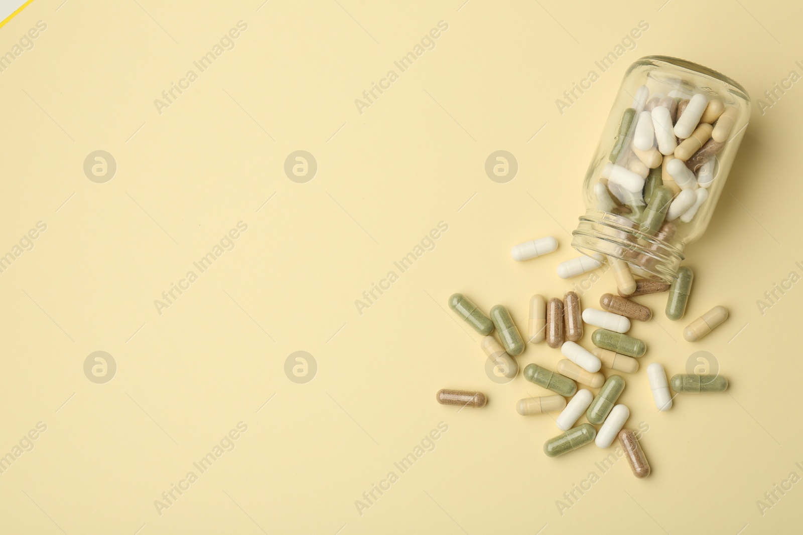 Photo of Vitamin pills and bottle on beige background, top view. Space for text