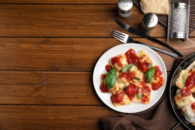 Tasty ravioli with tomato sauce served on wooden table, flat lay. Space for text