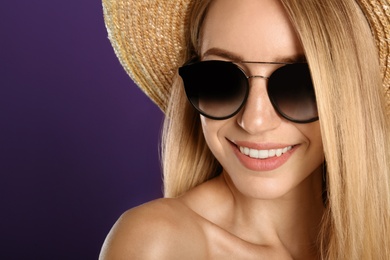 Photo of Beautiful woman in stylish sunglasses on purple background, closeup