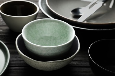 Stylish empty dishware on black wooden table