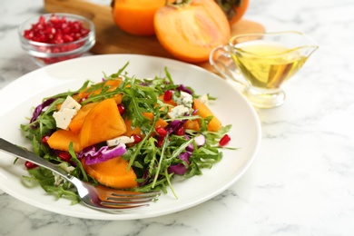 Photo of Delicious persimmon salad served on white marble table, closeup