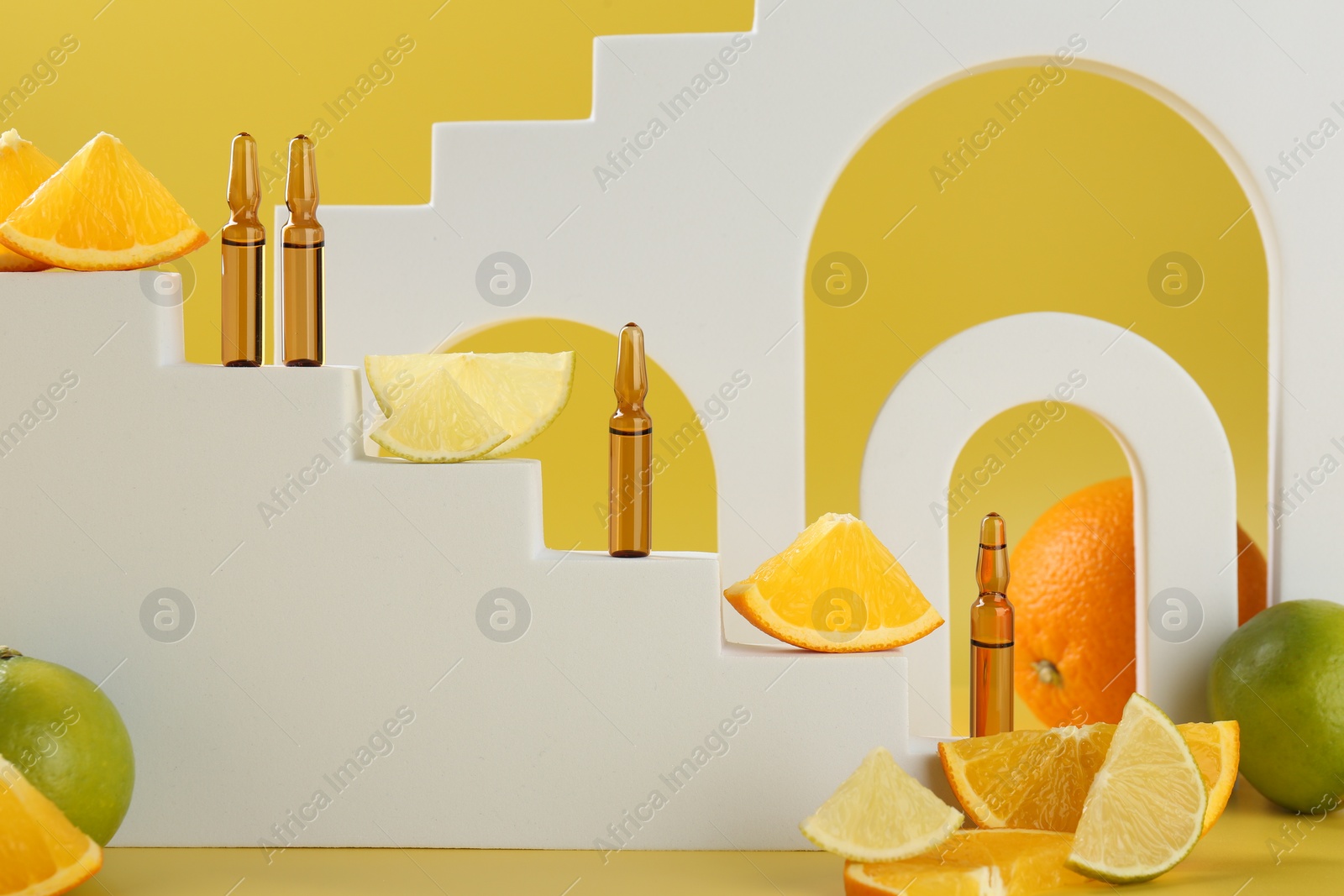 Photo of Stylish presentation of skincare ampoules with vitamin C and citrus slices on yellow background