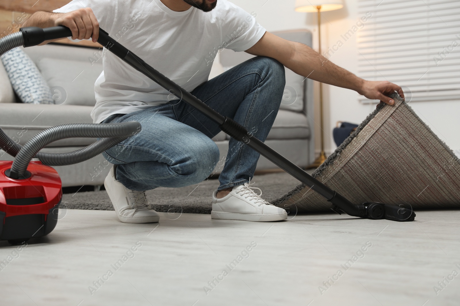 Photo of Young man using vacuum cleaner at home, closeup