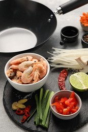 Different products and black wok on grey table, closeup