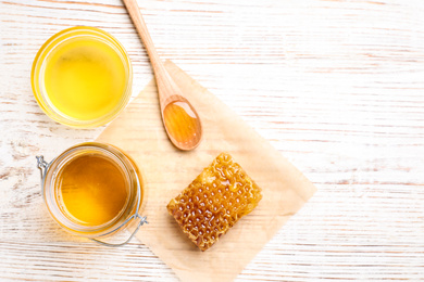 Photo of Tasty aromatic honey on white wooden table, flat lay. Space for text