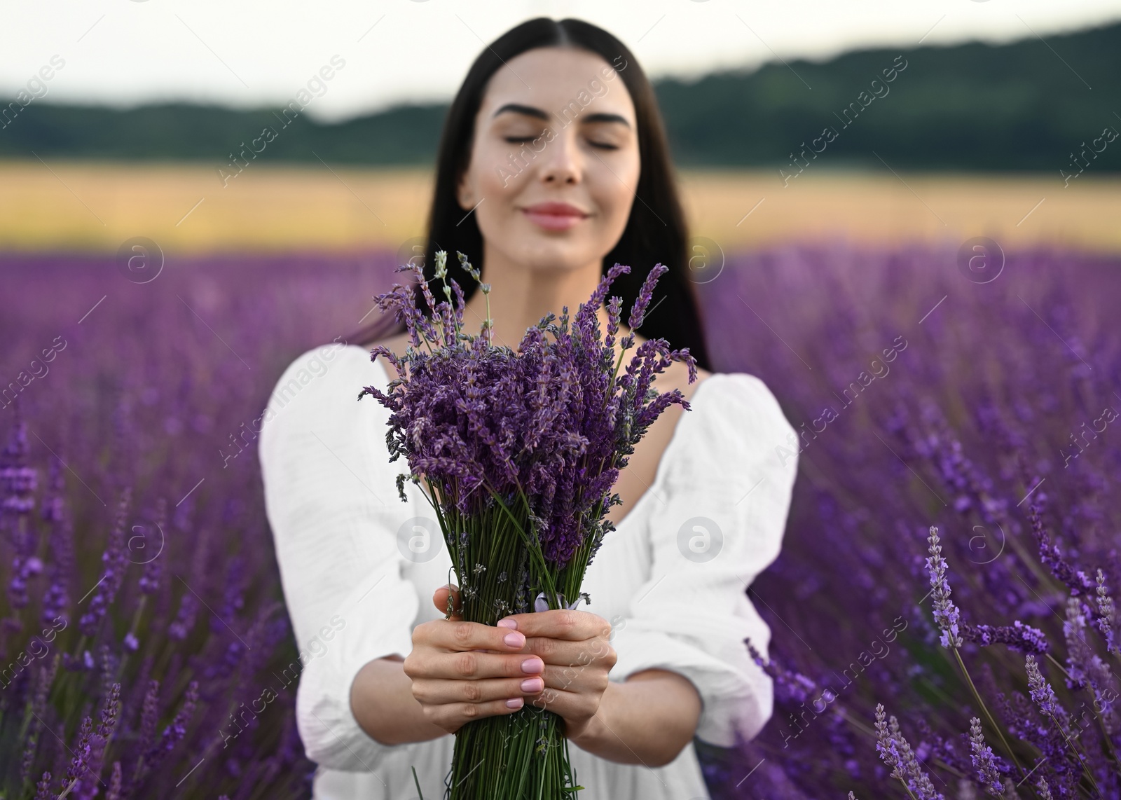 Photo of Beautiful young woman with bouquet in lavender field