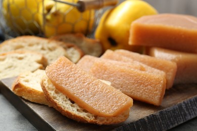 Photo of Tasty sweet quince paste, bread and fresh fruits on grey table, closeup