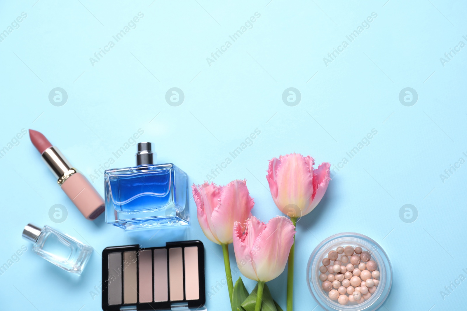 Photo of Flat lay composition with different makeup products and beautiful spring flowers on light blue background, space for text