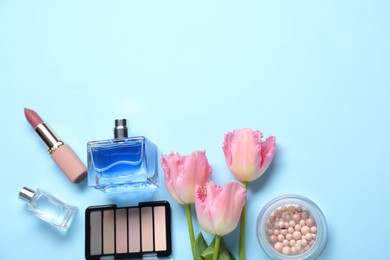 Photo of Flat lay composition with different makeup products and beautiful spring flowers on light blue background, space for text