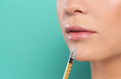 Photo of Young woman getting lips injection on color background, space for text. Cosmetic surgery