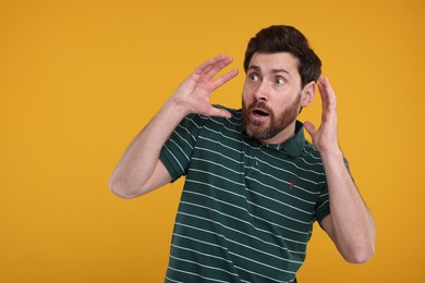 Portrait of surprised man on yellow background, space for text