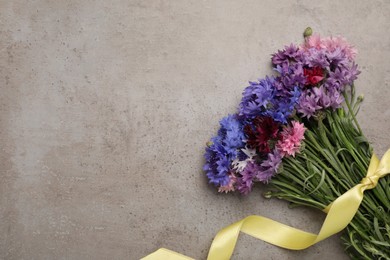 Photo of Bouquet of beautiful cornflowers on grey table, top view. Space for text