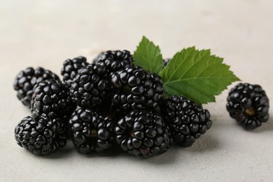 Pile of tasty ripe blackberries with leaves on white table