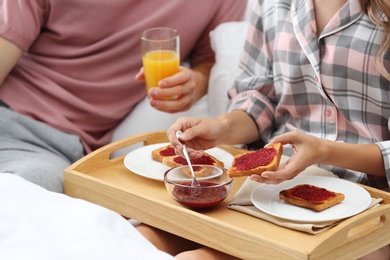 Happy young couple having romantic breakfast in bed at home, closeup