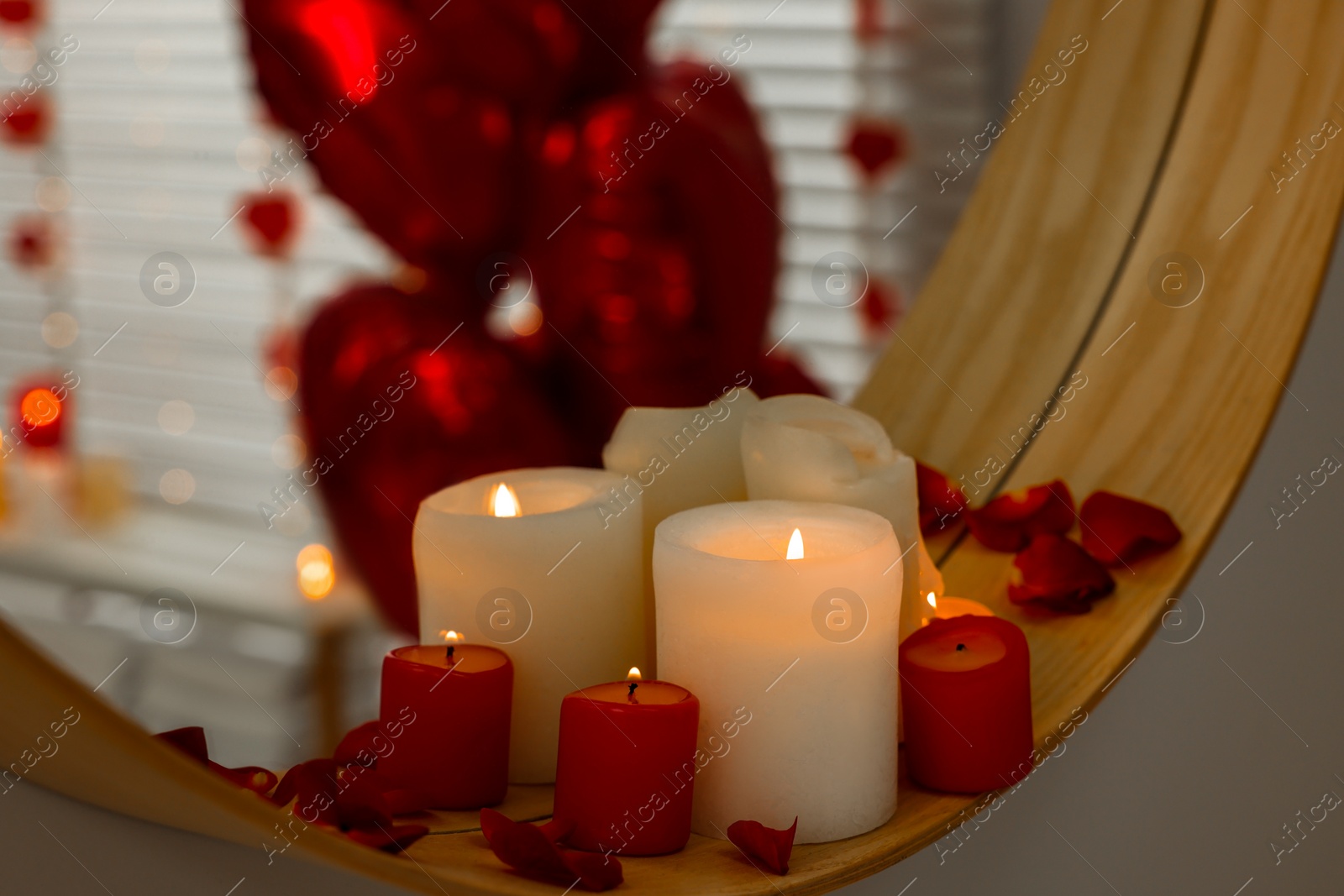 Photo of Mirror and burning candles in bathroom decorated for Valentine's day, closeup