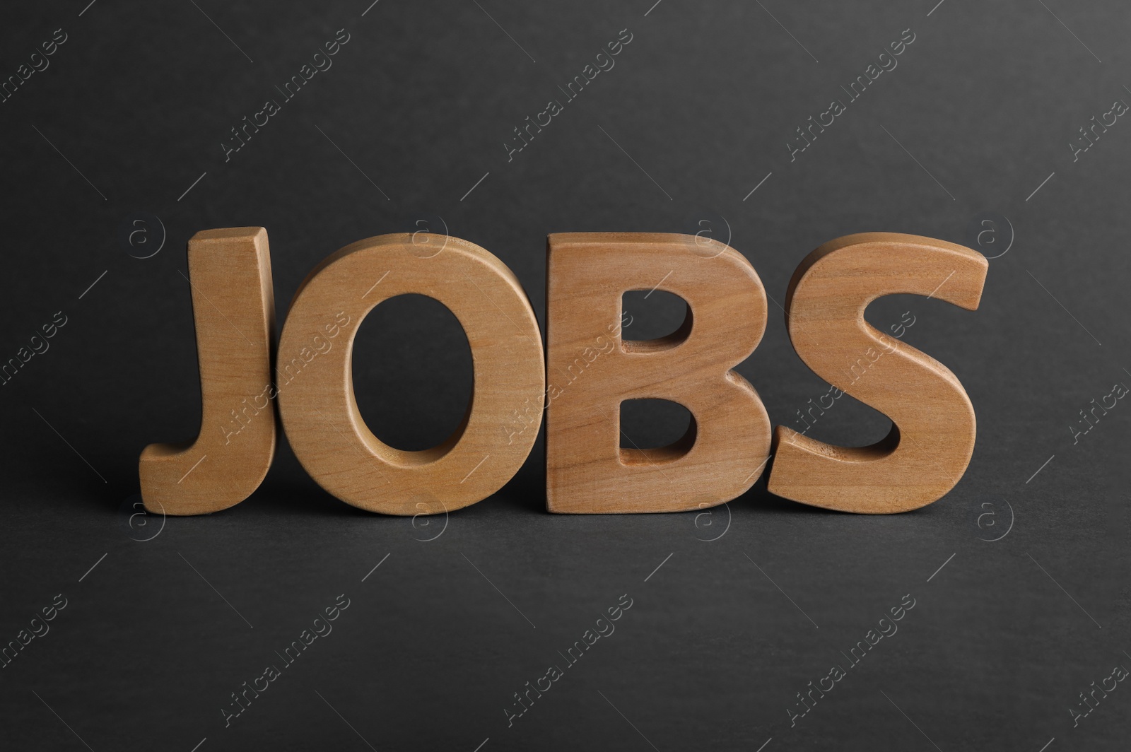 Photo of Word JOBS made with wooden letters on dark background. Career concept