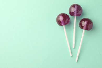 Photo of Tasty lollipops on turquoise background, flat lay. Space for text