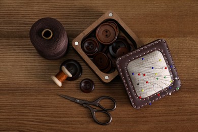 Photo of Set of sewing supplies and accessories on wooden table, flat lay