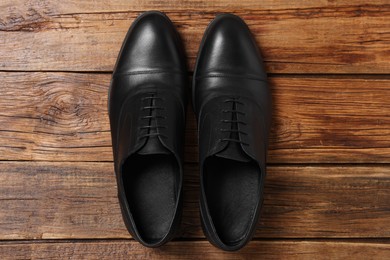 Photo of Pair of black leather men shoes on wooden background, top view