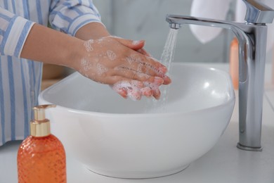 Woman washing hands with liquid soap in bathroom, closeup