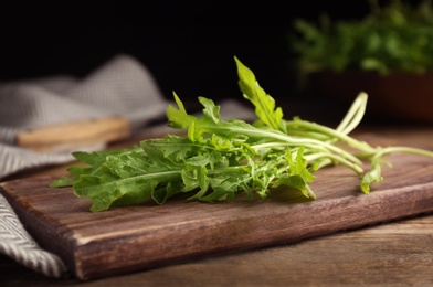 Photo of Fresh arugula and cutting board on wooden table