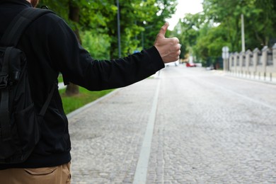 Man catching car on city street, closeup. Hitchhiking trip