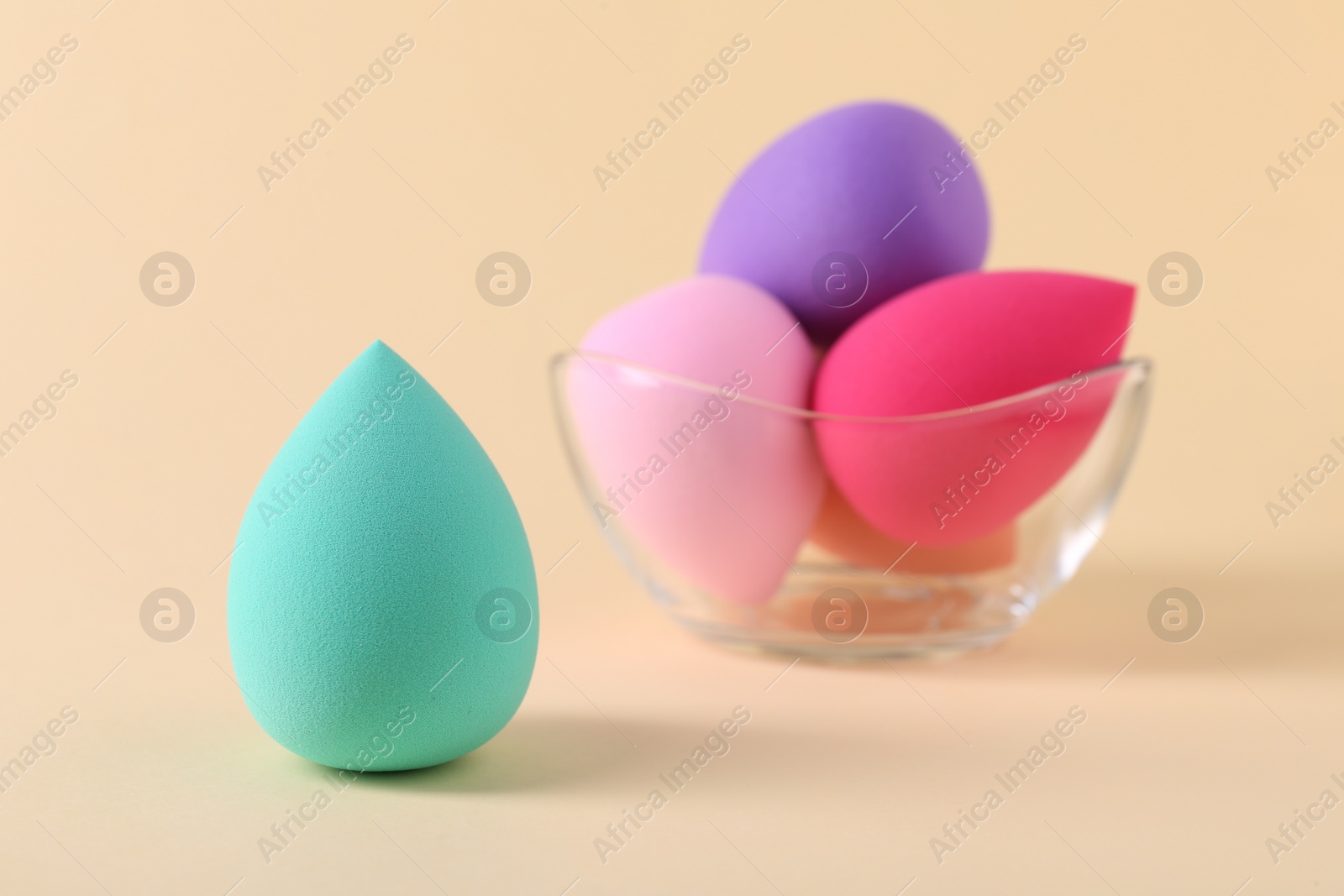 Photo of Colorful makeup sponges on beige background, closeup