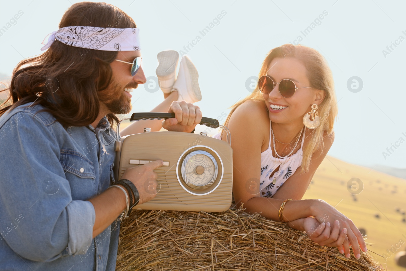 Photo of Happy hippie couple with radio receiver in field