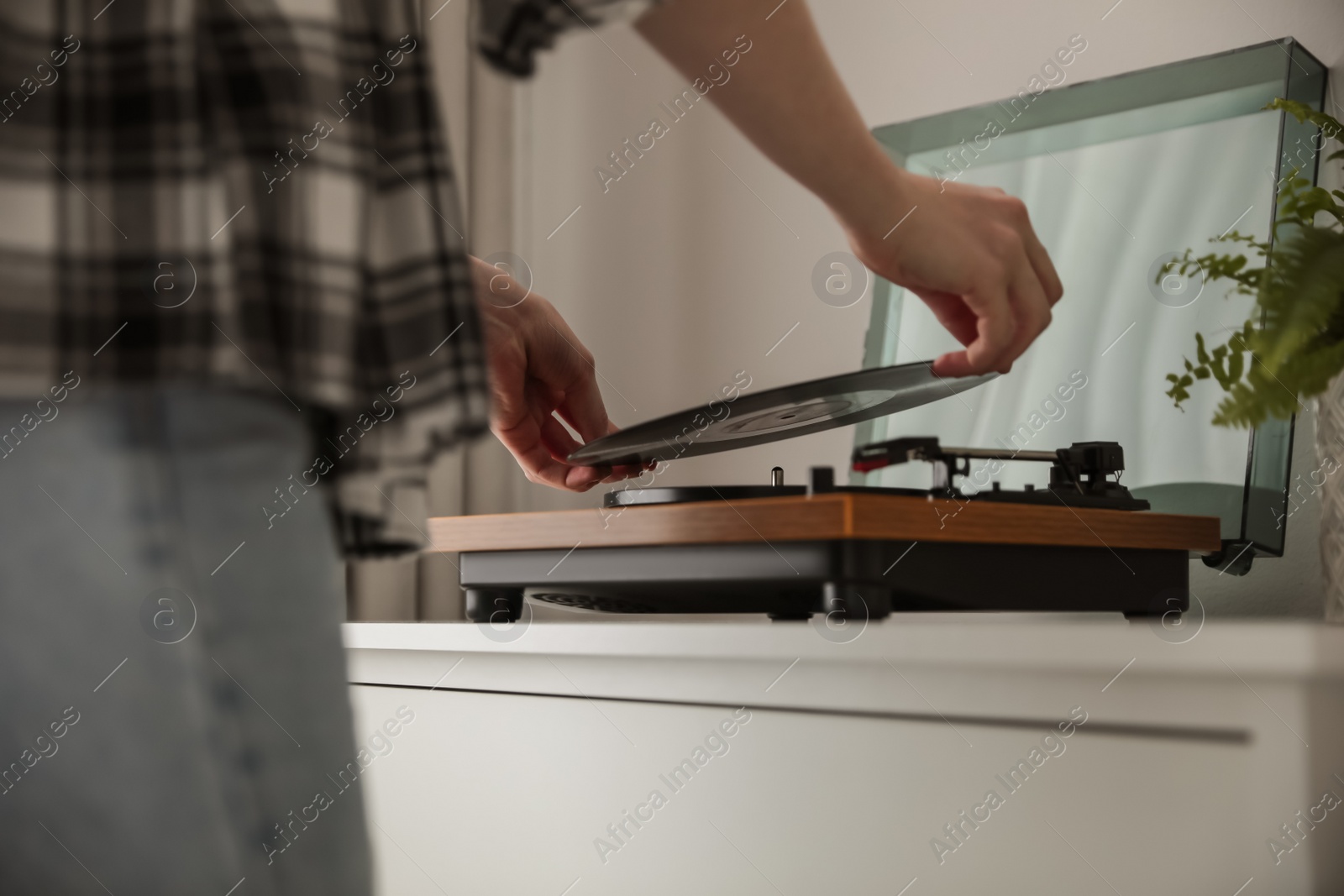 Photo of Young woman using turntable at home, closeup