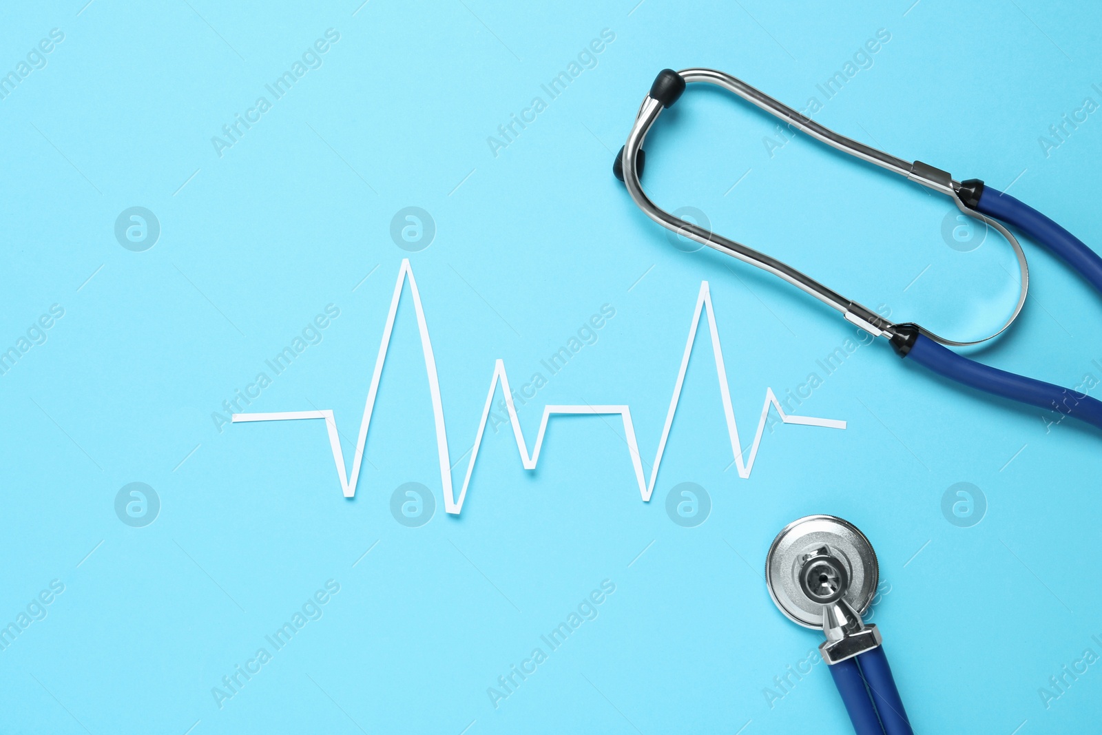 Photo of Paper cardiogram line and stethoscope on light blue background, flat lay