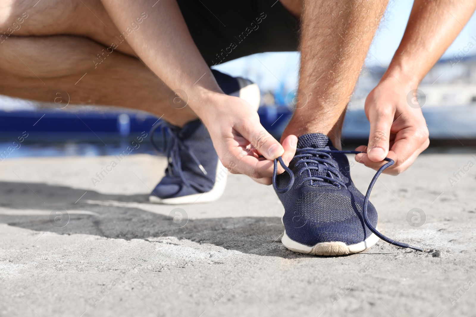 Photo of Sporty man tying shoelaces before running outdoors