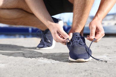 Sporty man tying shoelaces before running outdoors