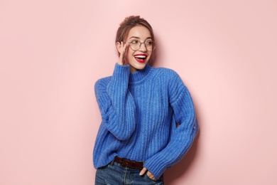 Beautiful young woman in warm sweater on color background