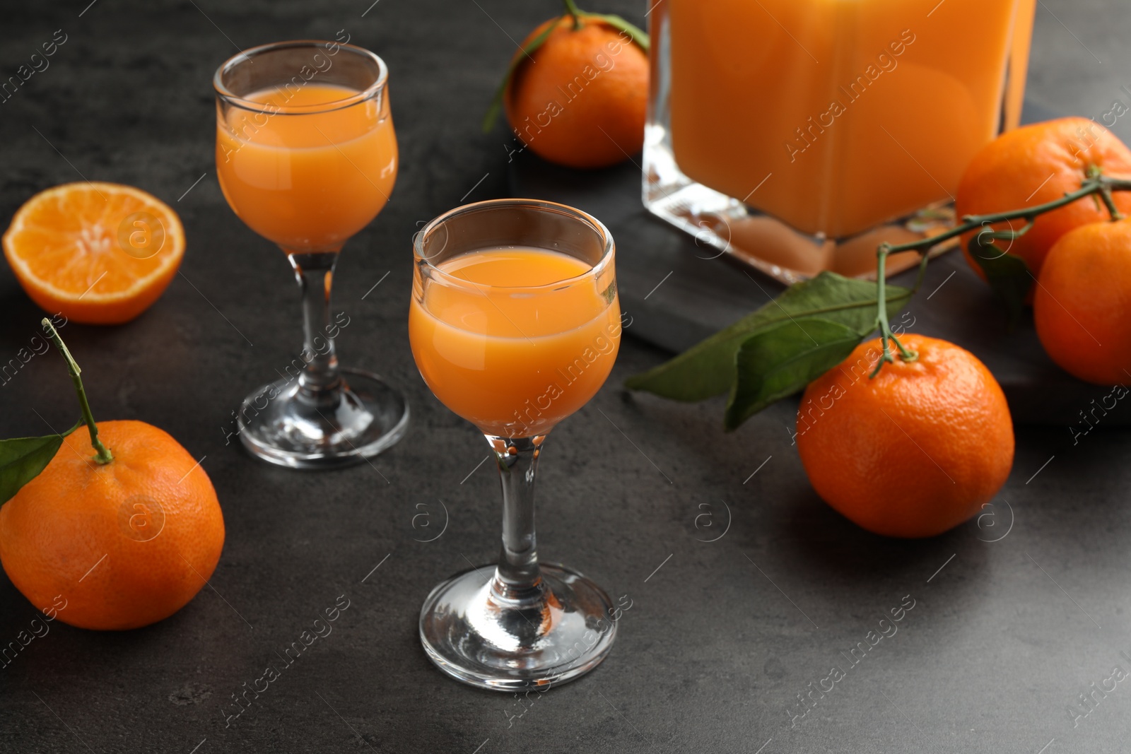 Photo of Delicious tangerine liqueur and fresh fruits on grey table